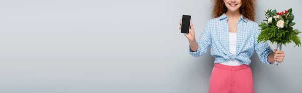 Vista ritagliata di donna che tiene fiori e smartphone con schermo bianco su sfondo grigio, banner — Foto stock