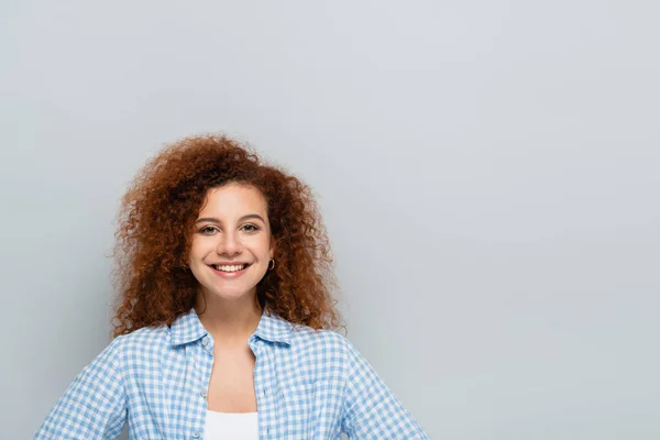 Curly woman in plaid shirt smiling at camera isolated on grey — Stock Photo