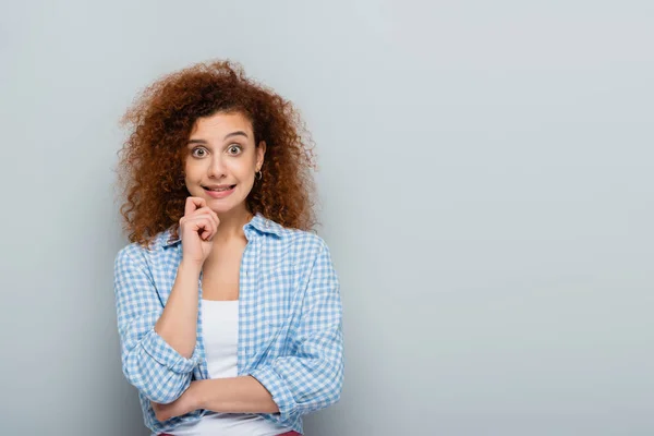 Discouraged woman holding hand near face while looking at camera on grey background — Stock Photo