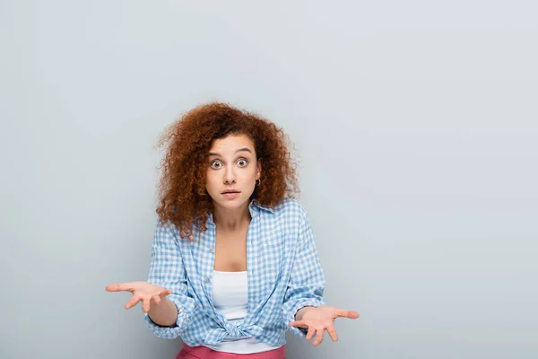 Astonished woman pointing with hands while looking at camera on grey background — Stock Photo