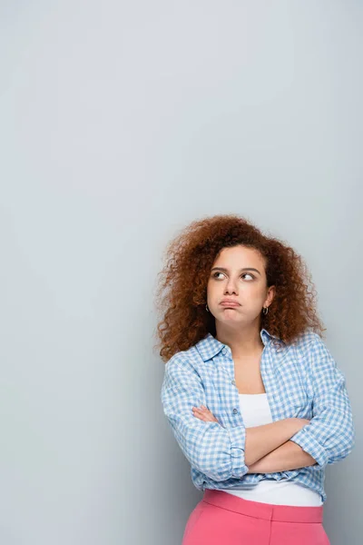 Upset woman standing with crossed arms and pouting lips on grey background — Stock Photo