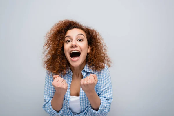 Thrilled woman showing win gesture and shouting isolated on grey — Stock Photo