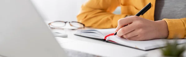 Partial view of freelancer writing in notebook on blurred foreground, banner — Stock Photo