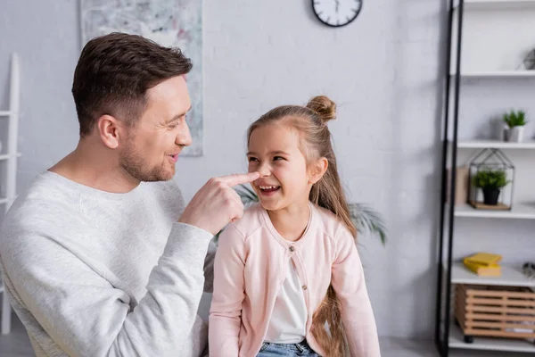 Uomo che tocca il naso di bambino positivo in soggiorno — Foto stock