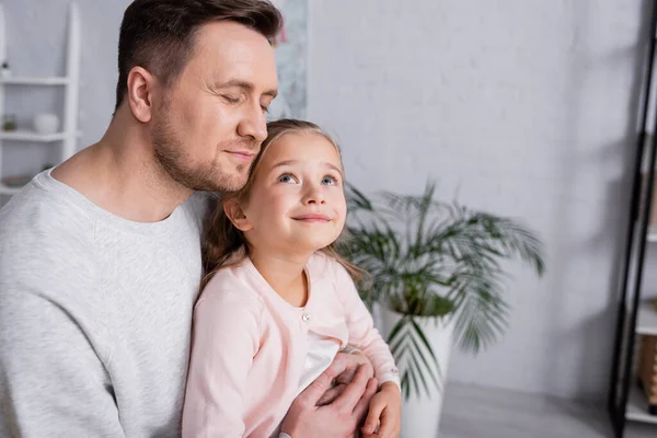 Padre con los ojos cerrados abrazando al niño sonriente - foto de stock