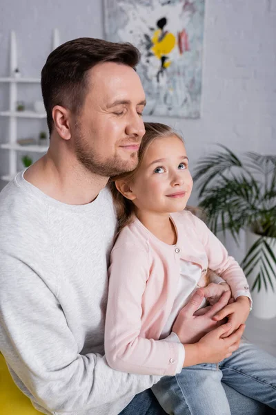 Lächelnde Tochter sitzt zu Hause auf dem Schoß des Vaters — Stockfoto