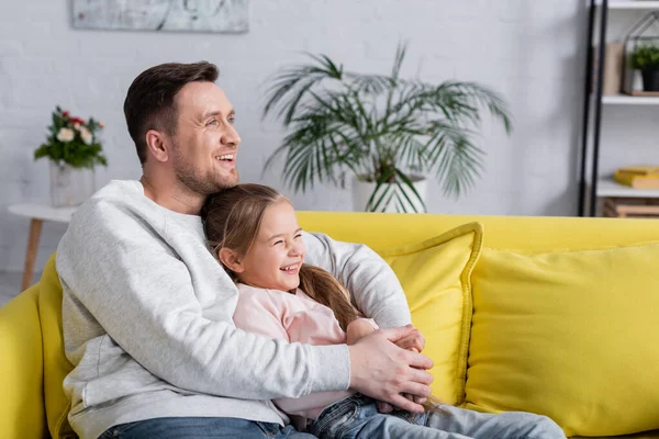 Niño feliz sentado cerca de padre en la sala de estar - foto de stock