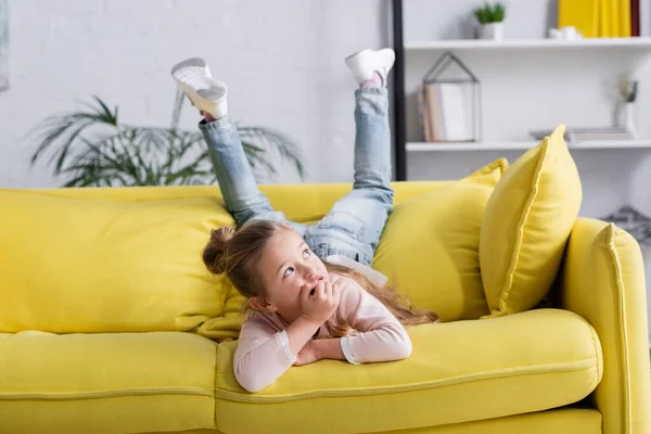 Мечтательный ребенок, лежащий дома на диване — стоковое фото