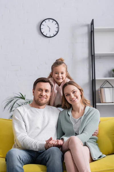 Famille joyeuse regardant la caméra dans le salon — Photo de stock