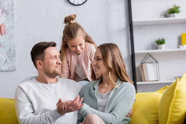 Smiling papers holding hands near daughter at home — Stock Photo