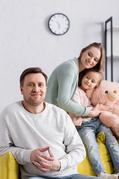Uomo guardando macchina fotografica vicino figlia e moglie su sfondo sfocato — Foto stock