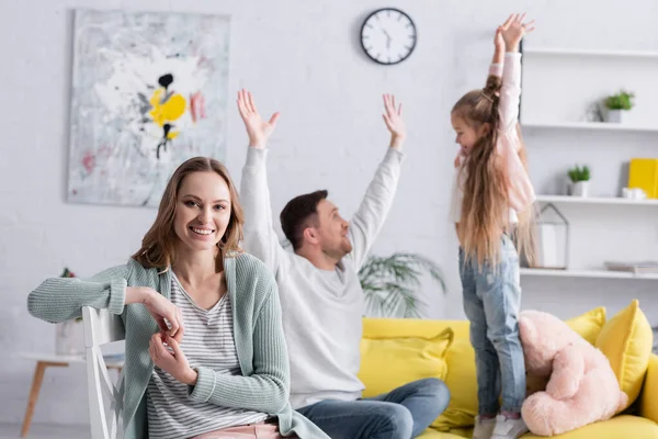 Smiling woman looking at camera near husband and daughter on blurred background — Stock Photo