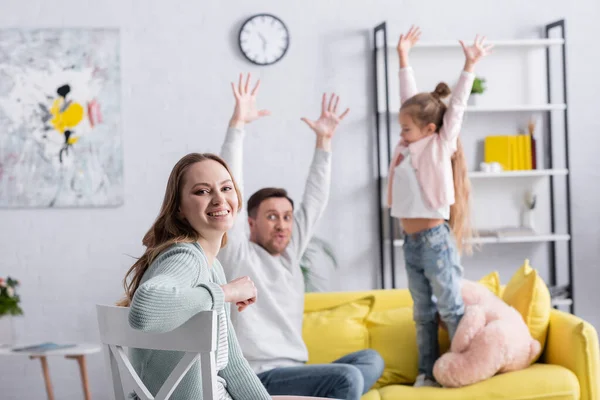 Femme joyeuse assise près de la famille sur fond flou — Photo de stock