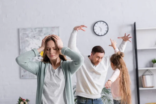 Femme fatiguée debout près de la famille s'amusant sur fond flou — Photo de stock