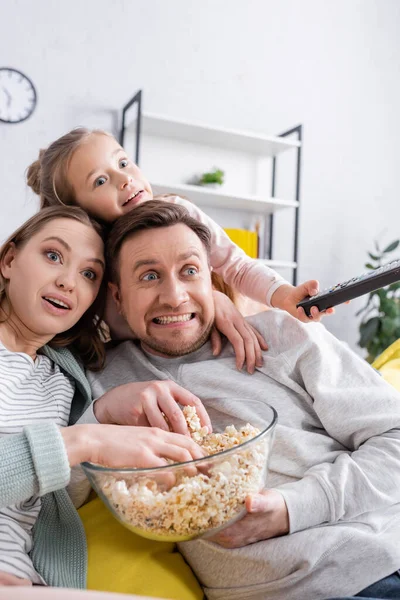 Smiling family with popcorn watching movie at home — Stock Photo