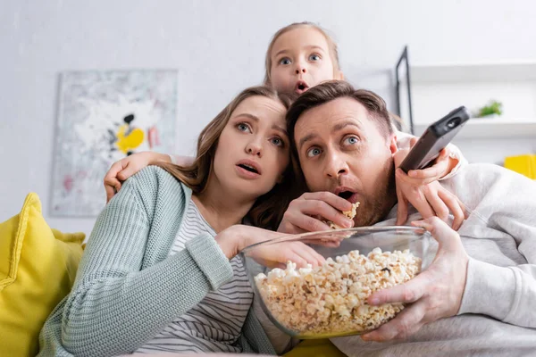 Scared family with popcorn watching film on couch — Stock Photo