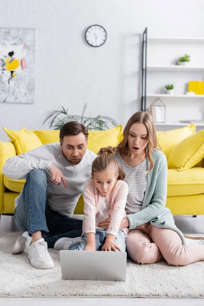 Erstaunte Familie benutzt Laptop auf dem Fußboden im Wohnzimmer — Stockfoto