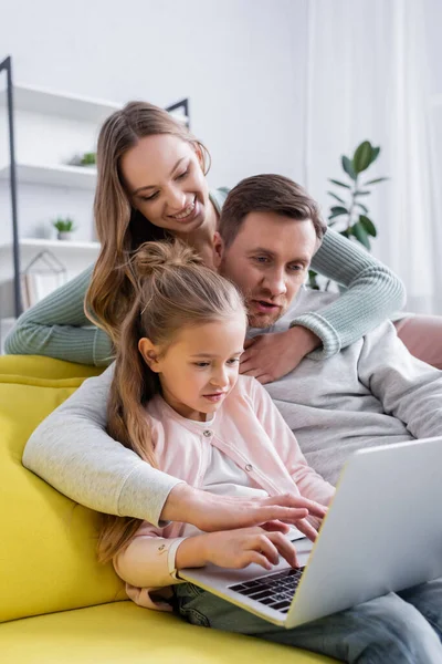 Femme étreignant mari en utilisant un ordinateur portable près de l'enfant à la maison — Photo de stock