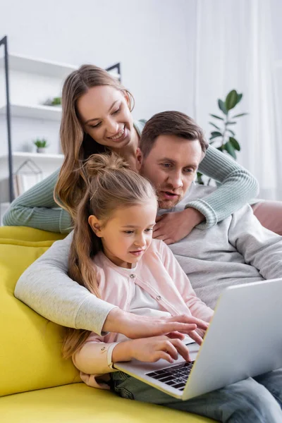 Woman hugging husband using laptop near child at home — Stock Photo