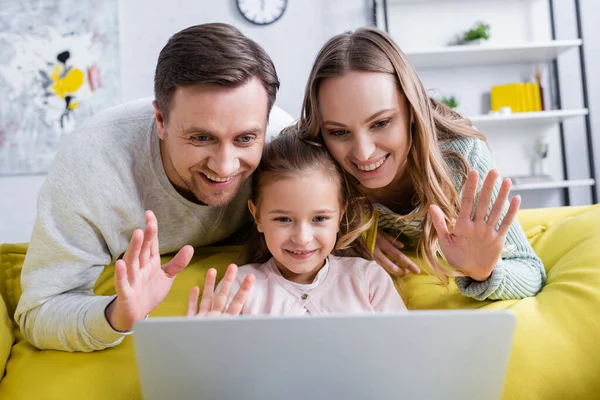 Familia alegre tener chat de vídeo en el ordenador portátil en la sala de estar - foto de stock