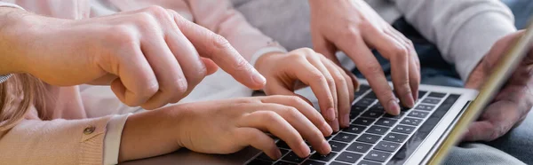 Cropped view of man pointing at laptop near wife and daughter, banner — Stock Photo