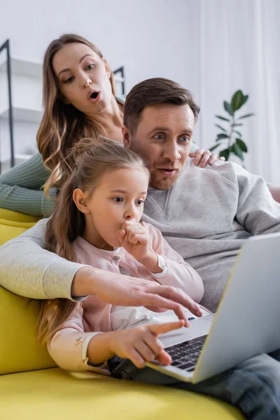 Astonished family using laptop on blurred foreground — Stock Photo