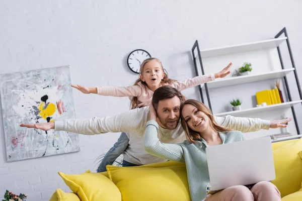 Homme et fille s'amuser près de sourire femme en utilisant un ordinateur portable à la maison — Photo de stock