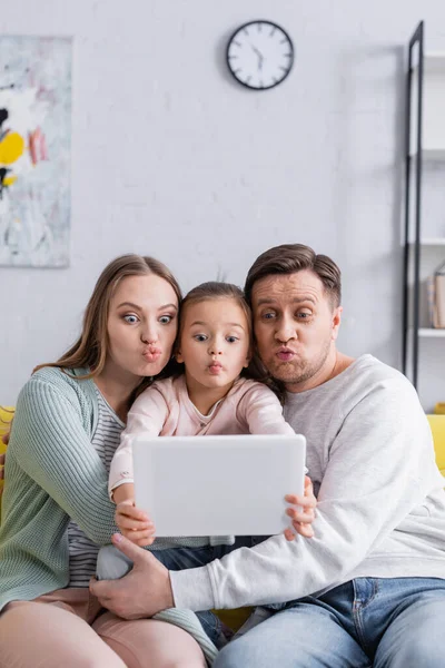 Family pouting lips while taking selfie on digital tablet on blurred foreground — Stock Photo