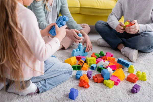 Vista cortada da família perto de blocos de construção coloridos no chão — Fotografia de Stock