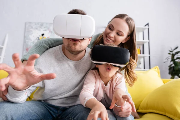 Enfant et père excités utilisant des casques vr près de la mère souriante — Photo de stock