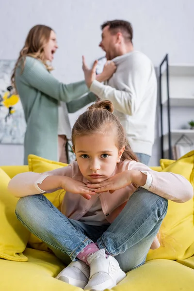 Trauriges Kind sitzt auf Couch in der Nähe von Eltern, die Streit haben — Stockfoto