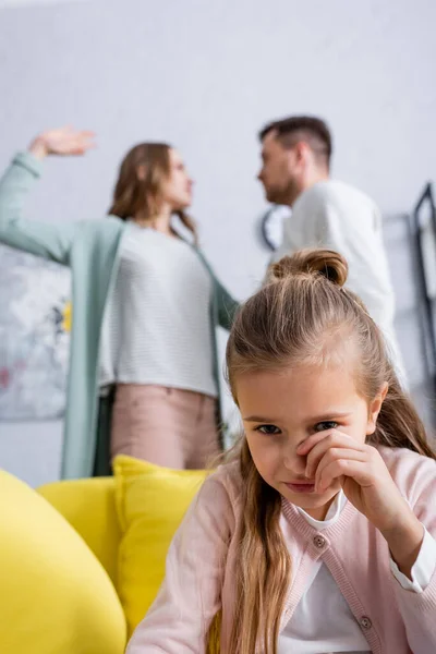 Piangere bambino seduto vicino ai genitori offuscati litigando — Foto stock