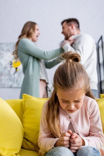 Dissatisfied child crying while parents quarrelling on blurred background — Stock Photo