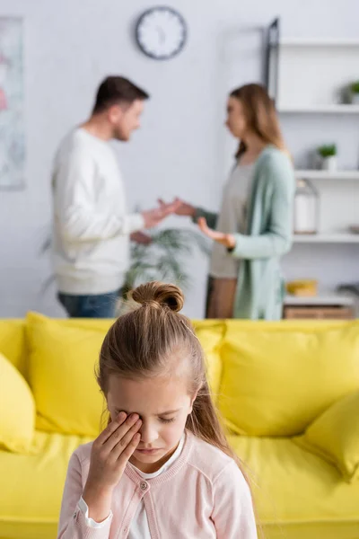 Hija llorando cerca de padres teniendo conflicto sobre fondo borroso - foto de stock