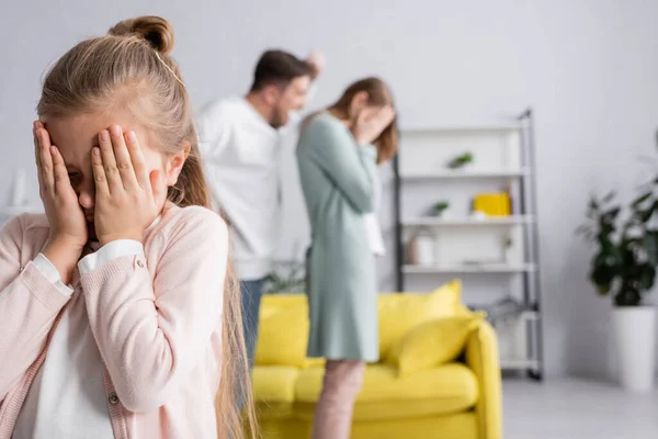 Mädchen verdeckt Gesicht, während Vater Mutter auf verschwommenem Hintergrund anschreit — Stockfoto