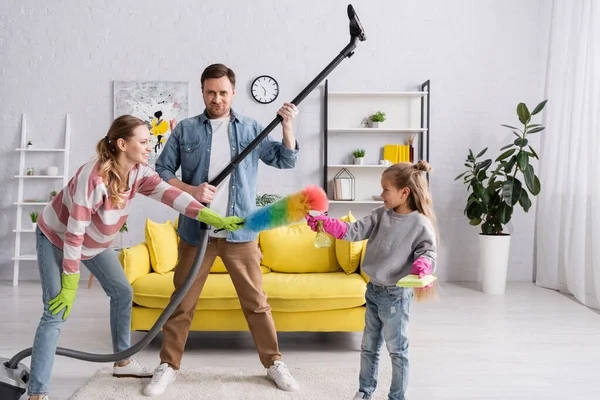 Smiling family holding cleaning supplies at home — Stock Photo