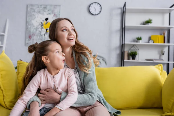 Excited mother hugging kid on yellow couch — Stock Photo