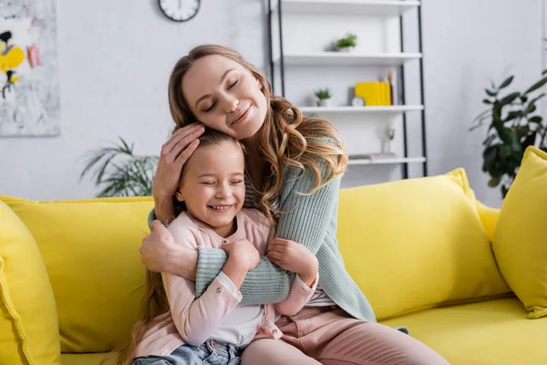 Madre feliz con los ojos cerrados abrazando niño - foto de stock