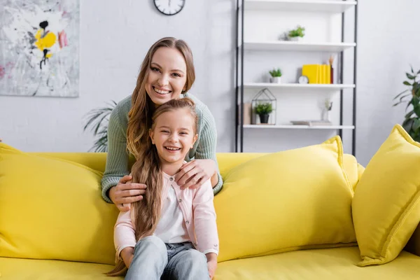 Positive Mutter und Kind blicken im Wohnzimmer in die Kamera — Stockfoto