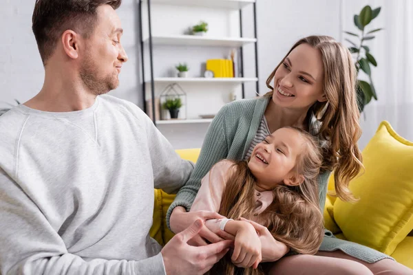 Mann schaut fröhliche Tochter und Ehefrau im Wohnzimmer an — Stockfoto