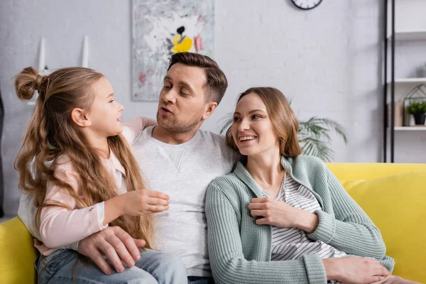 Bambino che parla con genitori sorridenti sul divano — Foto stock