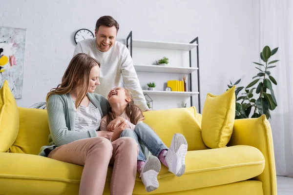 Les parents souriants passent du temps avec leur fille à la maison — Photo de stock