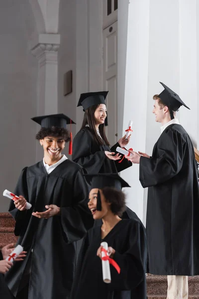 Asian graduate talking with friend in university — Stock Photo