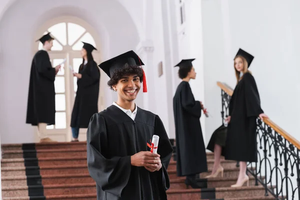 Junge afrikanisch-amerikanische Absolventin mit Diplom blickt in Universität in die Kamera — Stockfoto