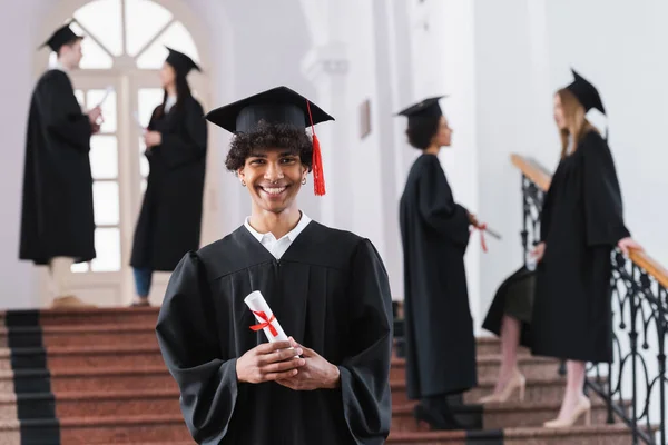 Soltero afroamericano con diploma sonriendo a la cámara - foto de stock