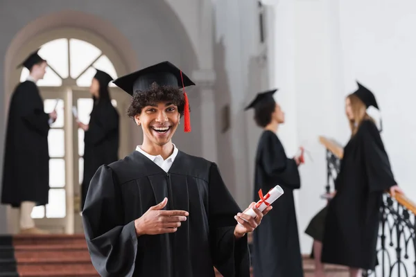Emocionado solteiro afro-americano apontando para diploma — Fotografia de Stock