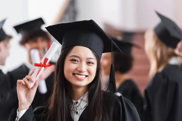 Positivo asiático estudiante holding diploma en la universidad - foto de stock