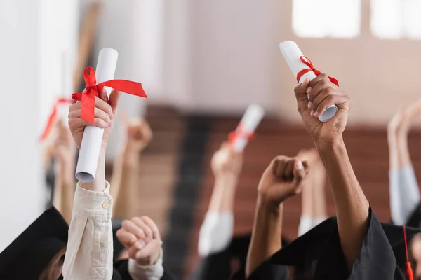 Cropped view of multiethnic students with diplomas showing yes gesture — Stock Photo