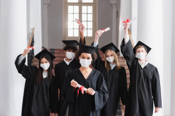 Licences interraciales en masques protecteurs titulaires de diplômes — Photo de stock