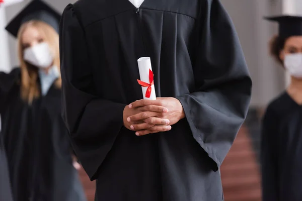 Vista cortada de estudante afro-americano em vestido acadêmico com diploma — Fotografia de Stock